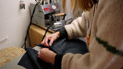 Seamstress-sewing-button-onto-clothing-top.-Wide-shot