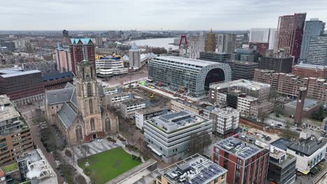 The-drone-is-flying-over-the-city-centre-of-Rotterdam-with-the-Markthal-in-the-centre-and-the-river-in-the-background-on-a-cloudy-day-in-Rotterdam-The-Netherlands-Aerial-Footage-4K