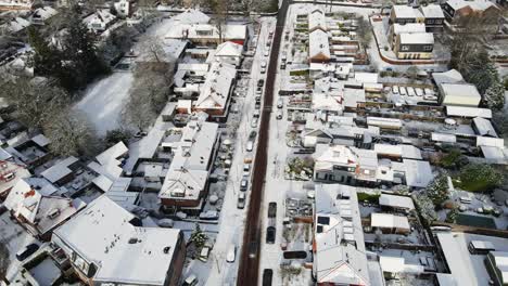 Aerial-of-car-driving-over-a-clean-road-in-a-beautiful-snow-covered-town