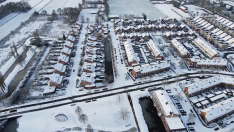Aerial-of-a-beautiful-suburban-neighborhood-covered-in-snow-with-a-car-driving-over-a-clean-road