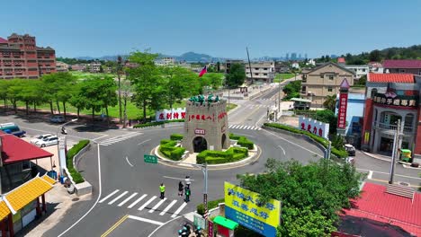 Luftaufnahme-Von-Menschen,-Die-Am-Kreisverkehr-In-Kinmen-Spazieren-Und-Das-Berühmte-Kriegsdenkmal-Mit-Wehender-Taiwanischer-Flagge-Beobachten