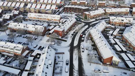 Drone-following-red-car-driving-through-a-beautiful-suburban-neighborhood-covered-in-snow