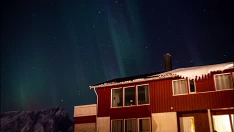 Aurora-Borealis,-Northern-Lights,-Amazing-Light-Show-in-Night-Sky-Above-traditional-Norwegian-wooden-building,-Lofoten,-Norway