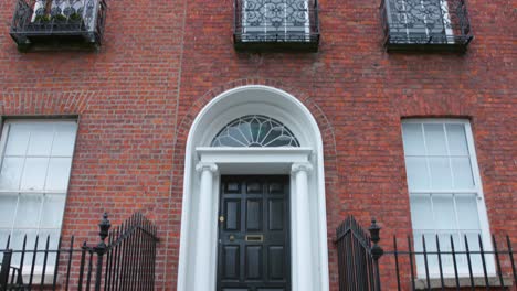 Puerta-Tradicional-Y-Pared-De-Ladrillo-Rojo-En-La-Fachada-De-La-Arquitectura-En-Dublín,-Irlanda