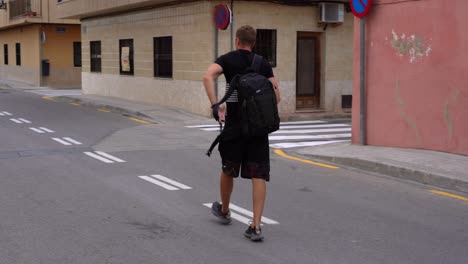 Tourist-picking-up-his-backpack-left-on-deserted-street-in-Valencia,-Spain