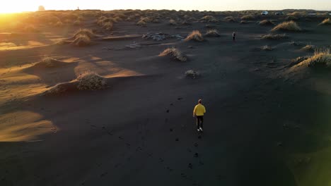 Young-man-walking-near-Vestrahorn-at-sunset,-Iceland