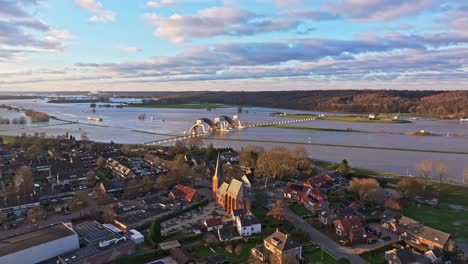 Flyover-drone-shot-over-the-town-and-church-of-Driel-with-the-weir-of-Driel-in-the-background-and-door-of-the-weir-open-during-high-waterlevels