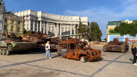 Mykhailivska-Square-filled-with-shelled-tanks-and-cars-from-the-Russia-Ukraine-war-in-Kyiv-city-center,-burned-and-destroyed-war-vehicles,-blue-sky-on-a-sunny-day,-4K-shot