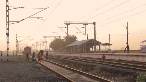 Still-shot-of-People-crossing-railway-tracks-at-a-Train-station-in-India-during-sunset-time