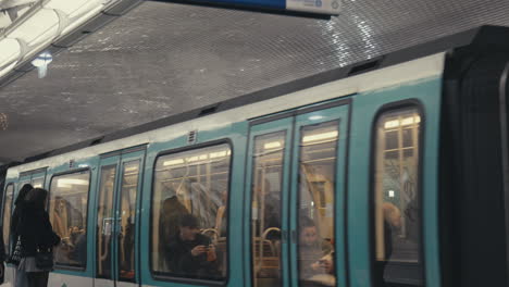 Schwenk-Nach-Unten,-Aufnahme-Eines-Zuges,-Der-An-Der-U-Bahn-Station-Nation-Ankommt,-Passagiere,-Die-Darauf-Warten,-Einzusteigen
