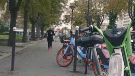 Una-Mujer-Blanca-Con-Auriculares-Pasa-Junto-A-Bicicletas-Urbanas-Estacionadas