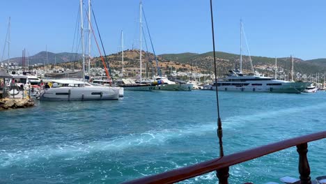 Bodrum-port-view-with-luxury-yachts-from-a-big-sailing-boat-in-Turkey,-fun-summer-vacation,-moving-boat,-fun-holiday-destination,-sunny-sea-day-with-blue-sky,-4K-shot