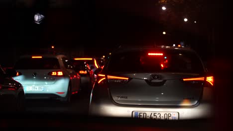 Car-stopping-on-vehicle-traffic-at-night-seen-from-a-taxi-cab-windshield,-Inside-vehicle-handheld-shot