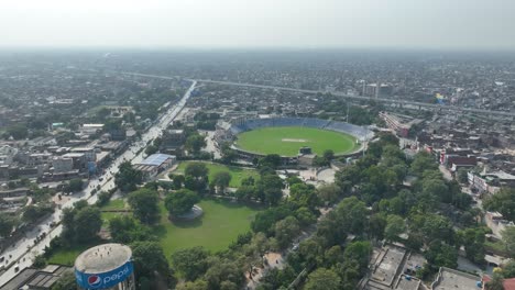Zoom-out-profile-view-of-cricket-stadium-in-between-Gujranwala-city-during-a-sunny-day-in-Punjab,-Pakistan