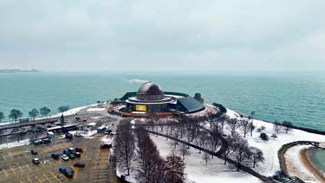 Aerial-view-approaching-the-Adler-Planetarium,-misty,-winter-day-in-Chicago,-USA