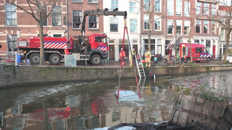 Firefighters-pulling-a-car-out-from-the-frozen-city-canal-using-a-mobile-crane