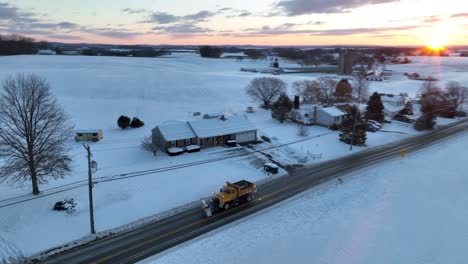 Yellow-snowplow-dump-truck-treats-snowy-rural-road-in-USA-with-salt
