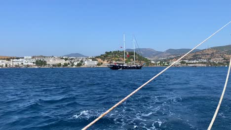 City-and-mountain-view-from-a-big-sailing-boat-in-Bodrum-Turkey,-fun-summer-vacation,-moving-boat,-luxury-holiday-destination,-sunny-sea-day-with-blue-sky,-4K-shot