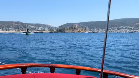 Wooden-stern-on-a-big-sailing-boat-in-Bodrum-Turkey-with-city-view,-fun-summer-vacation,-the-rear-back-of-a-moving-boat,-luxury-holiday-destination,-sunny-sea-day-with-blue-sky,-4K-shot