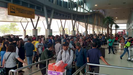 Busy-crowds-of-people,-taxi-drivers,-tourist-and-locals-waiting-outside-arrivals-terminal-at-Domine-Eduard-Osok-Airport-in-Sorong,-province-of-West-Papua,-Indonesia