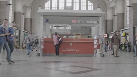 Passengers-walk-past-a-DB-information-desk-in-a-bustling-train-station