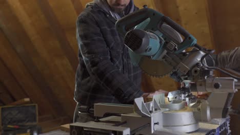 Carpenter-Cutting-Wood-On-A-Mitre-Saw,-Sawdust-Flying