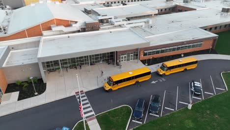 Gelbe-Schulbusse-Am-Eingang-Der-High-School-In-Amerika