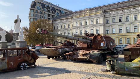 Mykhailivska-Square-filled-with-shelled-tanks-and-cars-from-the-Russia-Ukraine-war-in-Kyiv-city-center,-burned-and-destroyed-war-vehicles,-big-missile-rocket,-sunny-day,-4K-shot