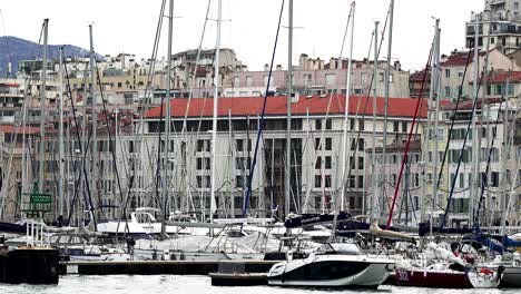 Boat-marina-and-buildings-with-people-tending-to-yachts,-Handheld-close-view-from-boat