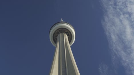 Upward-view-of-the-CN-Tower-in-Toronto,-Canada-against-a-clear-blue-sky,-with-wispy-clouds