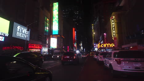 POV-shot-driving-in-middle-of-stores-and-illuminated-ads,-night-in-New-York,-USA