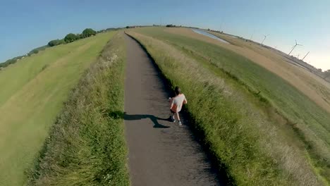 Dynamic-immersive-follow-swirling-camera-changing-angles-and-perspective-showing-a-male-trail-runner-on-floodplains-valley-dyke
