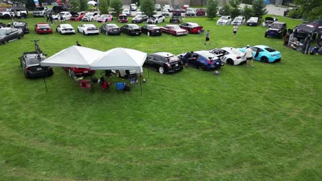 Aerial-shot-of-outdoor-car-show-and-event-with-pole-tents-in-summer-park