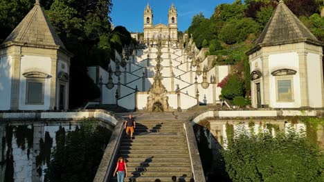 Aerial-View-of-Bom-Jesus-Stairclimb-in-Braga,-Northern-Portugal,-with-Two-Joggers-climbing-towards-Sanctuary