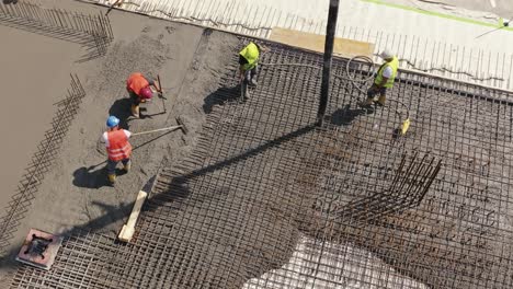 Workers-in-a-safety-vests-concretes-foundation,-rebar,-pour-cement-mortar-on-reinforcing-mesh-or-cage-from-pump-concrete-mixer
