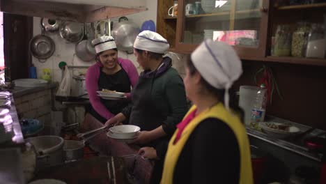 Drei-Einheimische-Frauen-Stehen-In-Der-Küche-Eines-Restaurants-Und-Kochen-Fröhlich-Die-Traditionelle-Cuzceño-Küche-Mit-Schweinefleisch-In-Cuzco,-Peru