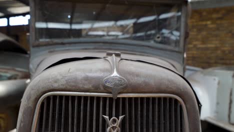 Old-rusting-vintage-radiator-grill-and-front-of-classic-car-in-a-storage-garage