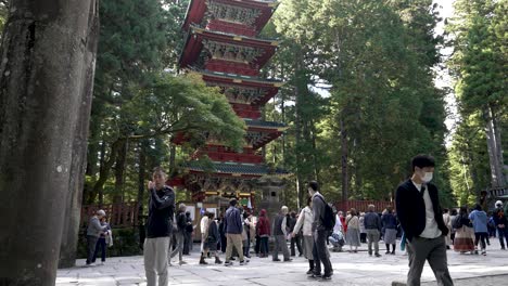 Tourists-leisurely-walk-near-the-Five-Storied-Pagoda-in-Nikko,-Japan,-surrounded-by-a-picturesque-forest-setting