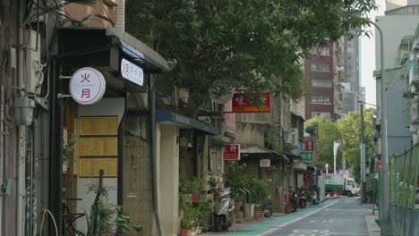 Quiet-street-in-Taiwan-with-signs-in-Chinese,-trees,-and-a-serene-atmosphere,-Pan-shot