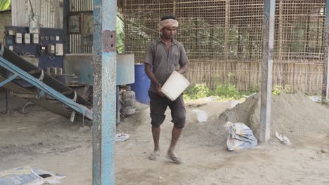 Indian-worker-in-poor-working-conditions-collecting-clay-sand-in-construction-site-building-with-a-bucket