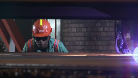 Ein-Afrikanischer-Stahlwerksarbeiter-In-Schutzkleidung-überwacht-Einen-Industriellen-Plasmaschneider,-Der-Ein-Stahlblech-Durchschneidet
