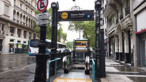 Entrance-to-the-subway-Saenz-Peña-station-in-downtown-under-the-rain-with-buses-on-the-streets-of-the-city