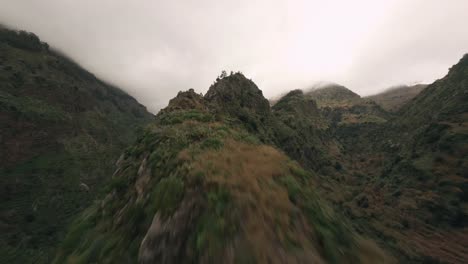 Dron-Fpv-Volando-En-Las-Montañas-Nubladas-Sobre-Una-Cresta-Montañosa-Cerca-De-Los-Exuberantes-árboles-Y-Rocas-Verdes