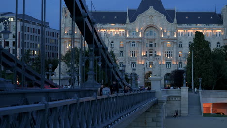 Pedestrians-cross-chain-bridge-in-city-of-Budapest-in-the-evening