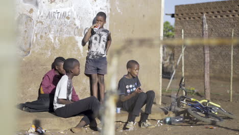 Four-young-boys-sit-outside-a-township-spaza-shop-drinking-coca-cola-and-chatting