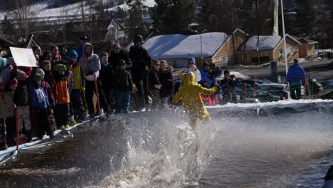 Teen-skis-down-a-snow-hill-and-across-a-pool-of-water-at-a-community-event-in-slow-motion