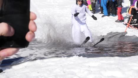 Man-skis-down-a-snow-hill-and-across-a-freezing-pool-of-water-in-slow-motion