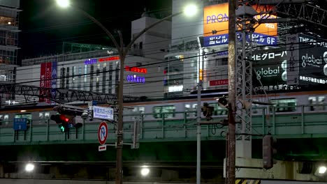 Traversing-an-elevated-rail-in-Shinjuku,-Japan,-a-train-unveils-the-enchanting-allure-of-the-nocturnal-cityscape
