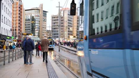 Electric-tram-pulls-out-of-Central-Station-in-downtown-Oslo,-Norway-on-a-wet,-winter-day