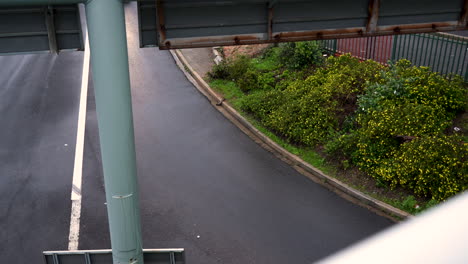 Overhead-shot-of-small-white-motor-car-taking-motorway-off-ramp-exit-in-wet,-rainy-weather